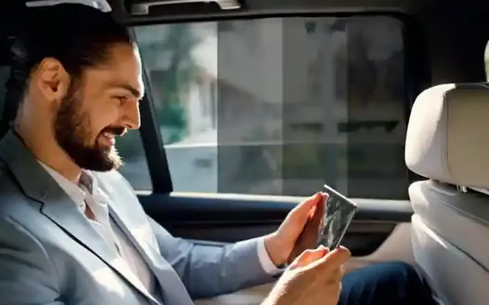 A passenger relaxing in the back seat of a car fitted with 3M automotive window film that cuts heat and glare