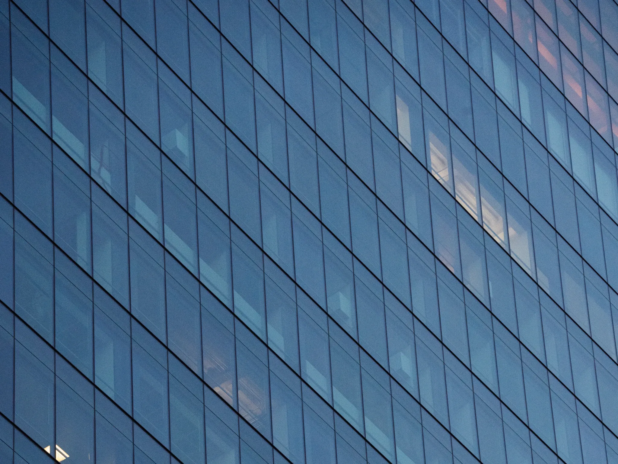 Blue glass office facade with structured grid at dusk