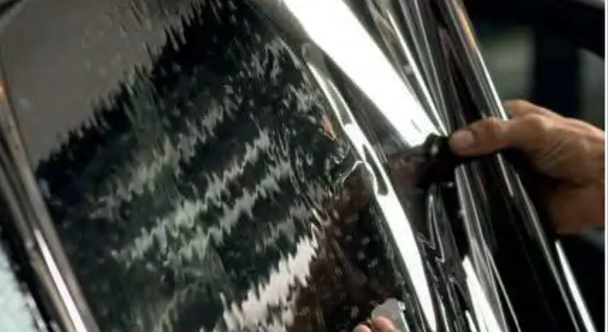 Ceramic tint film being squeegeed onto a car door window