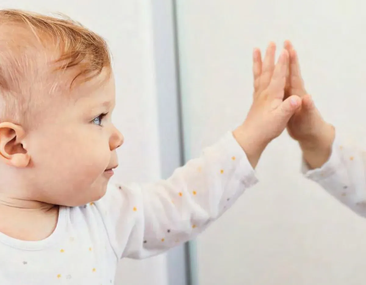A small child with both hands pressed flat against a glass door