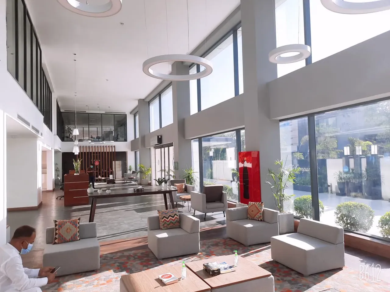 A double height office lounge behind filmed glass, bright with the view to the street kept