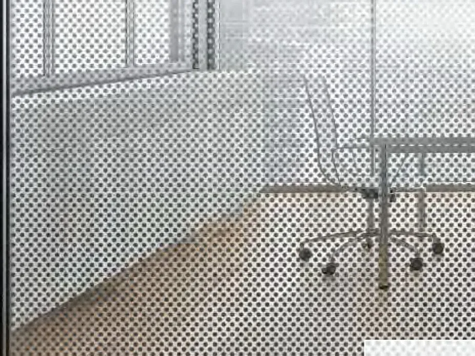 Dotted frost film across an office partition: the desk chair behind it reads only as a soft shape, and the room stays bright