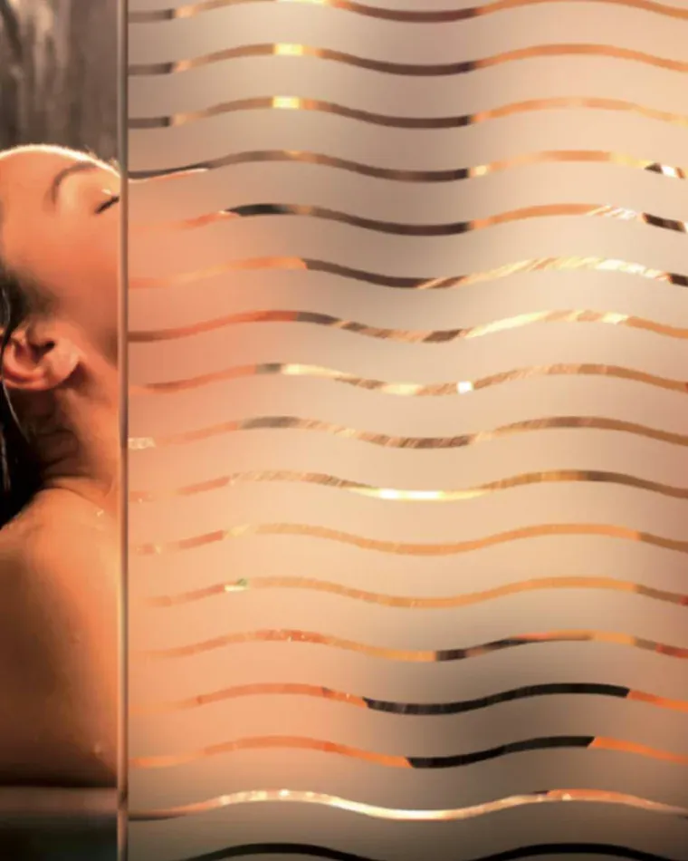 Wave-pattern frosted film on a shower screen, figure softened behind it