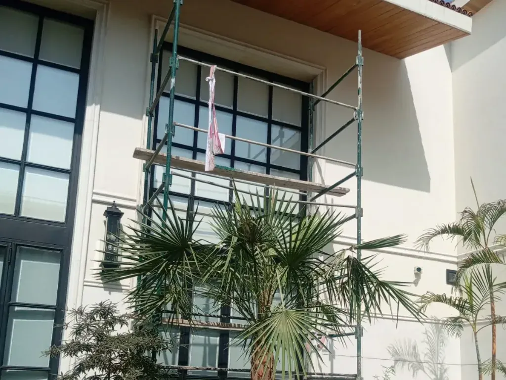 An access tower set up against the tall courtyard window of a Lahore home on fitting day