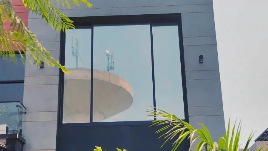 Tall filmed glazing on a house, mirroring the sky when seen from the street