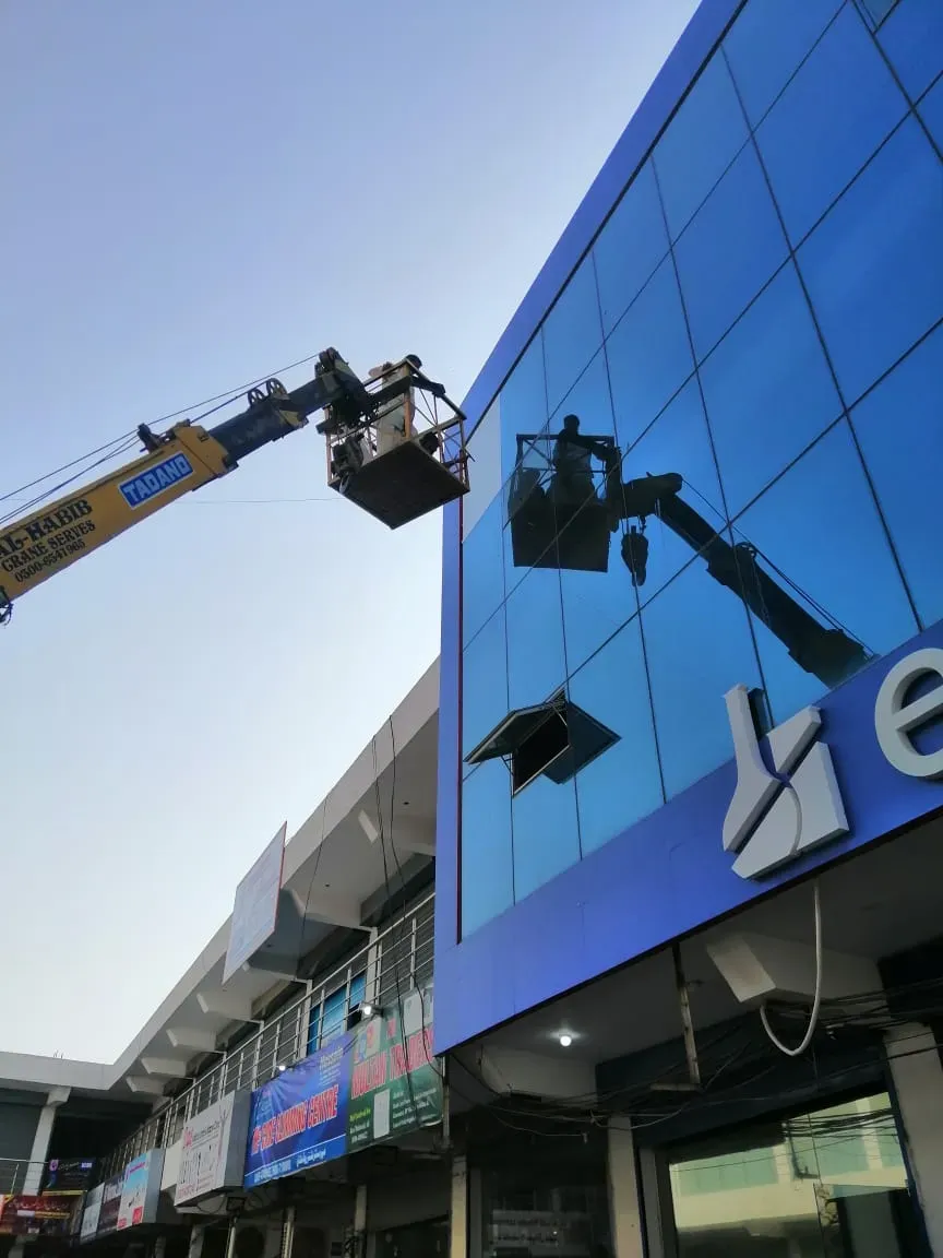 A Protek crew filming a blue reflective facade from a truck mounted boom lift
