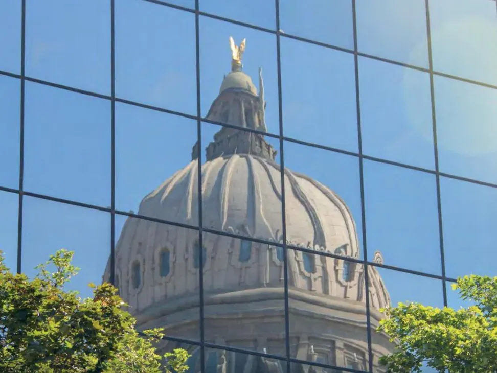 Mirror film on a glass facade reflecting the dome of the building opposite, so nothing inside is visible from the street