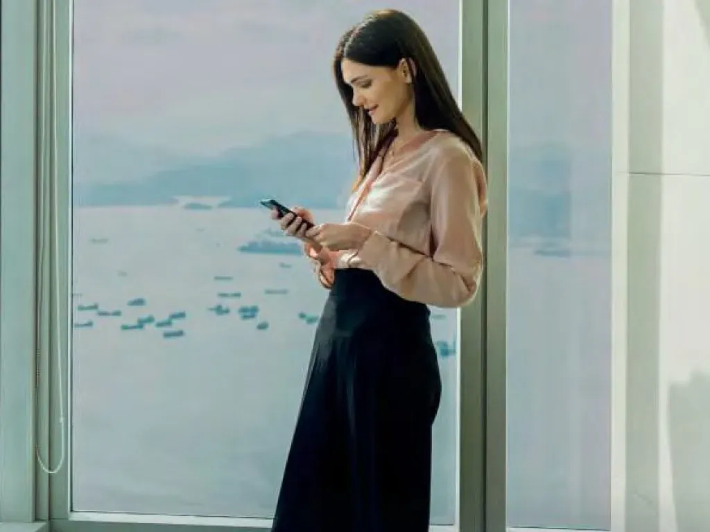 Woman standing at tinted floor to ceiling office glazing, looking out over the water while the tint keeps the room hidden from outside